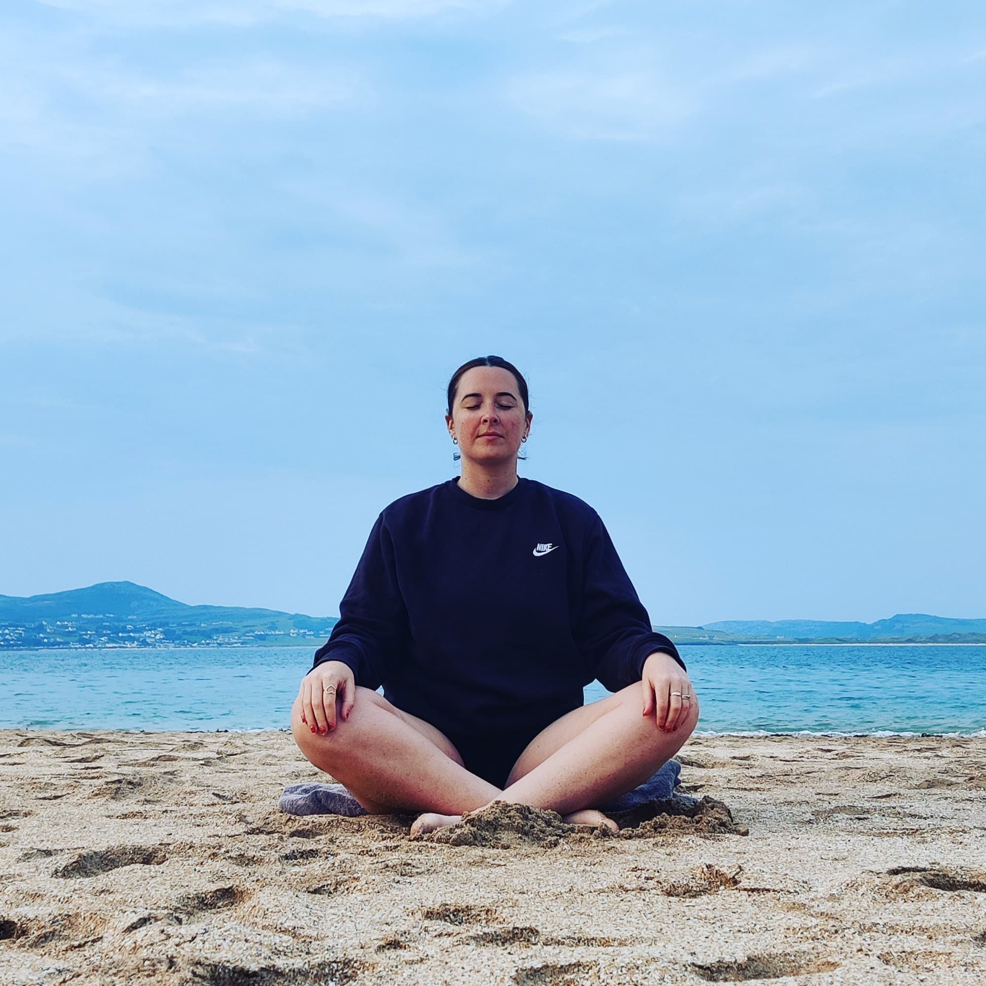 Photo of Mary Bradley on the beach meditating Ireland