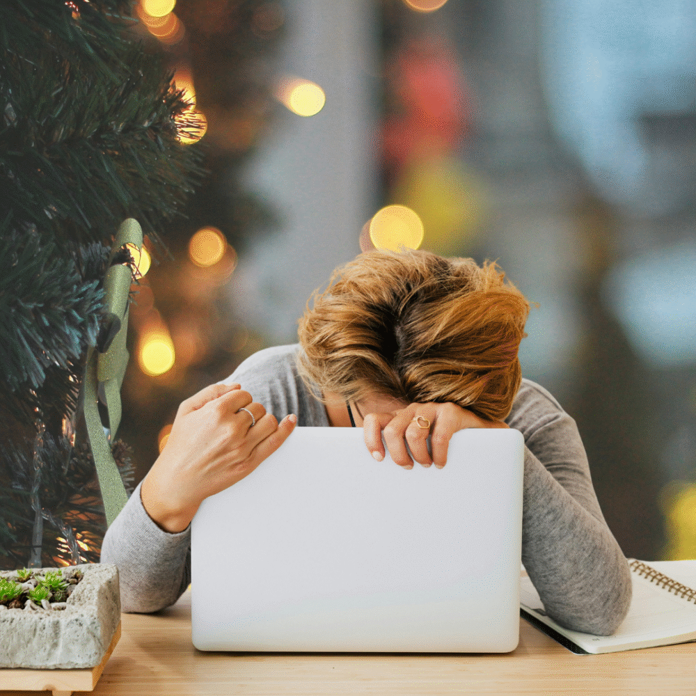 Parent hanging head over laptop with christmas background. stressed with pressure of work and christmas coming.